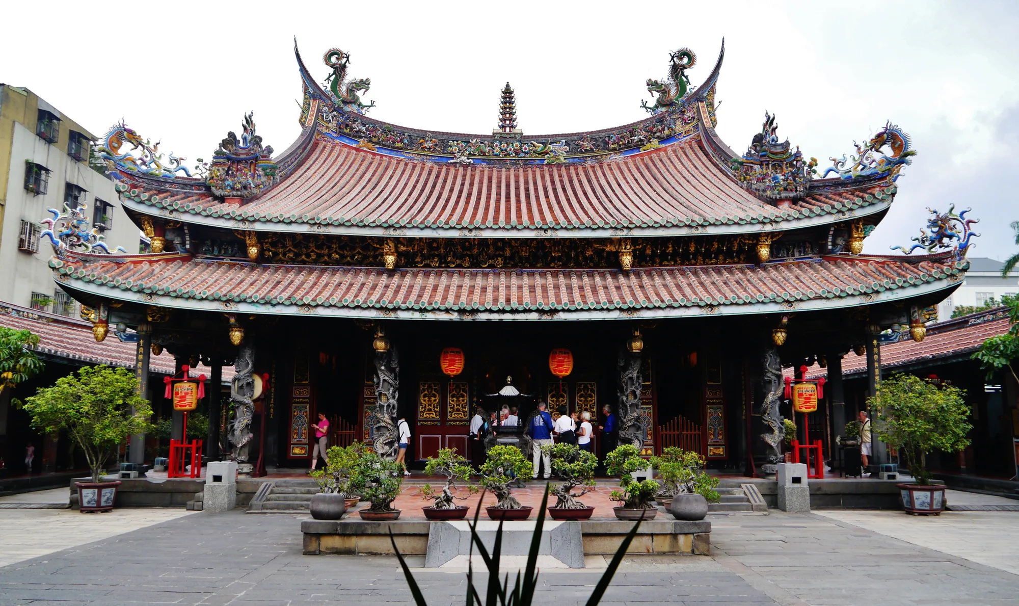 The ornate main hall of Dalongdong Bao'an Temple in Taipei, with a multi-tiered swallowtail roof, dragon ornaments and red lanterns