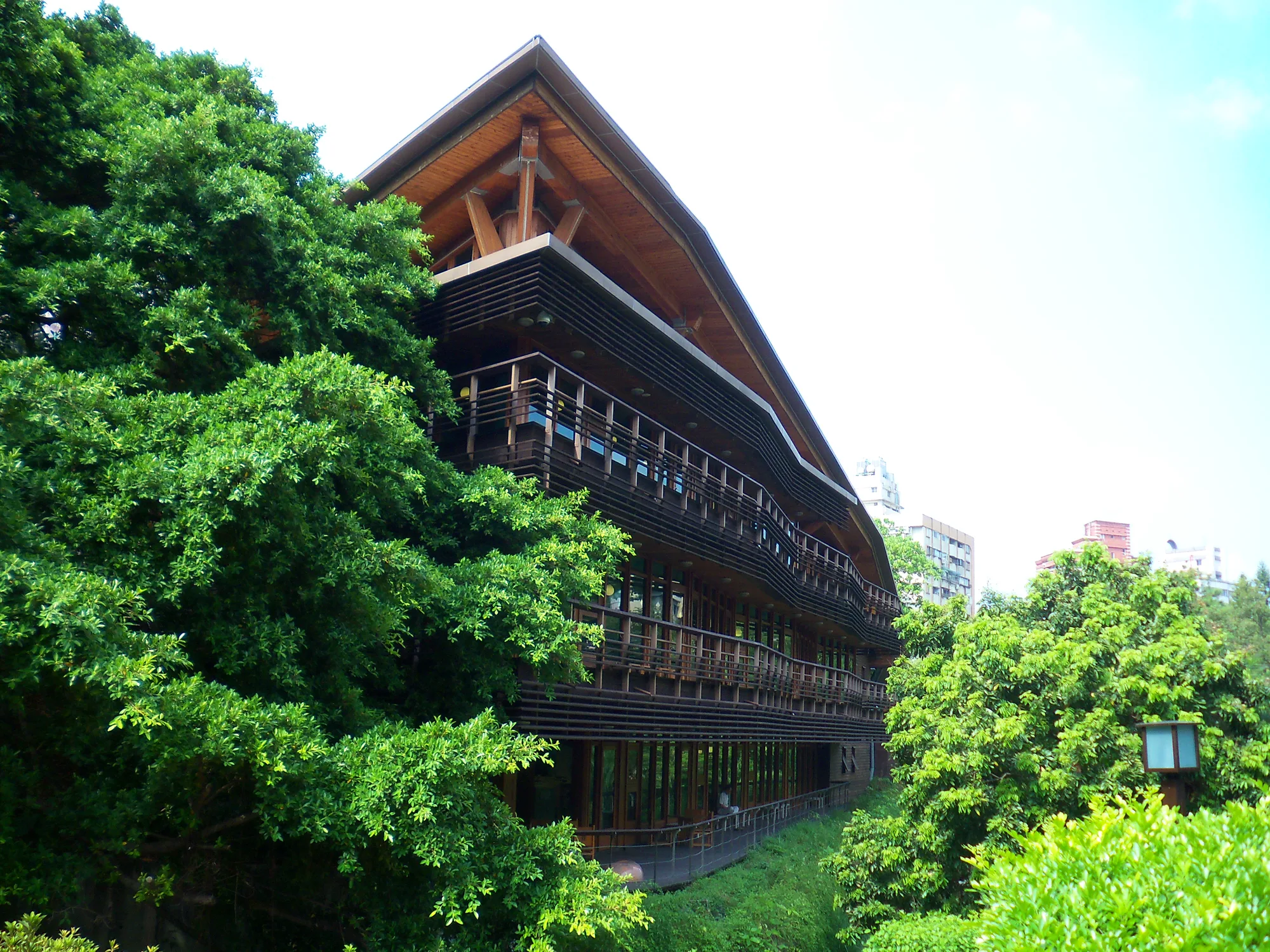 The green wooden eco-library of the Taipei Public Library Beitou Branch, with timber-slatted balconies framed by trees