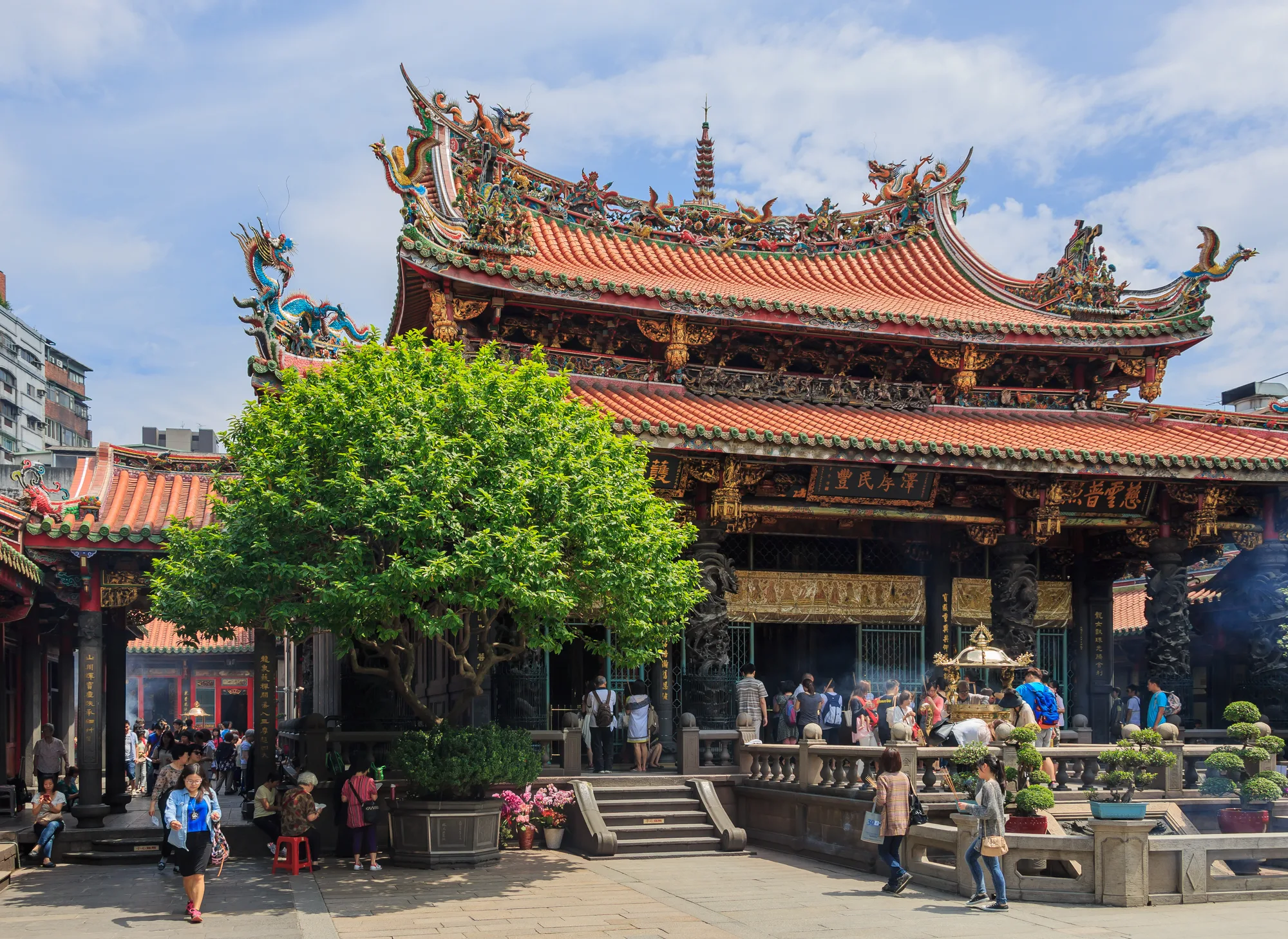 The ornate main hall of Longshan Temple in Wanhua, Taipei, with a dragon-decorated multi-tiered roof and red columns