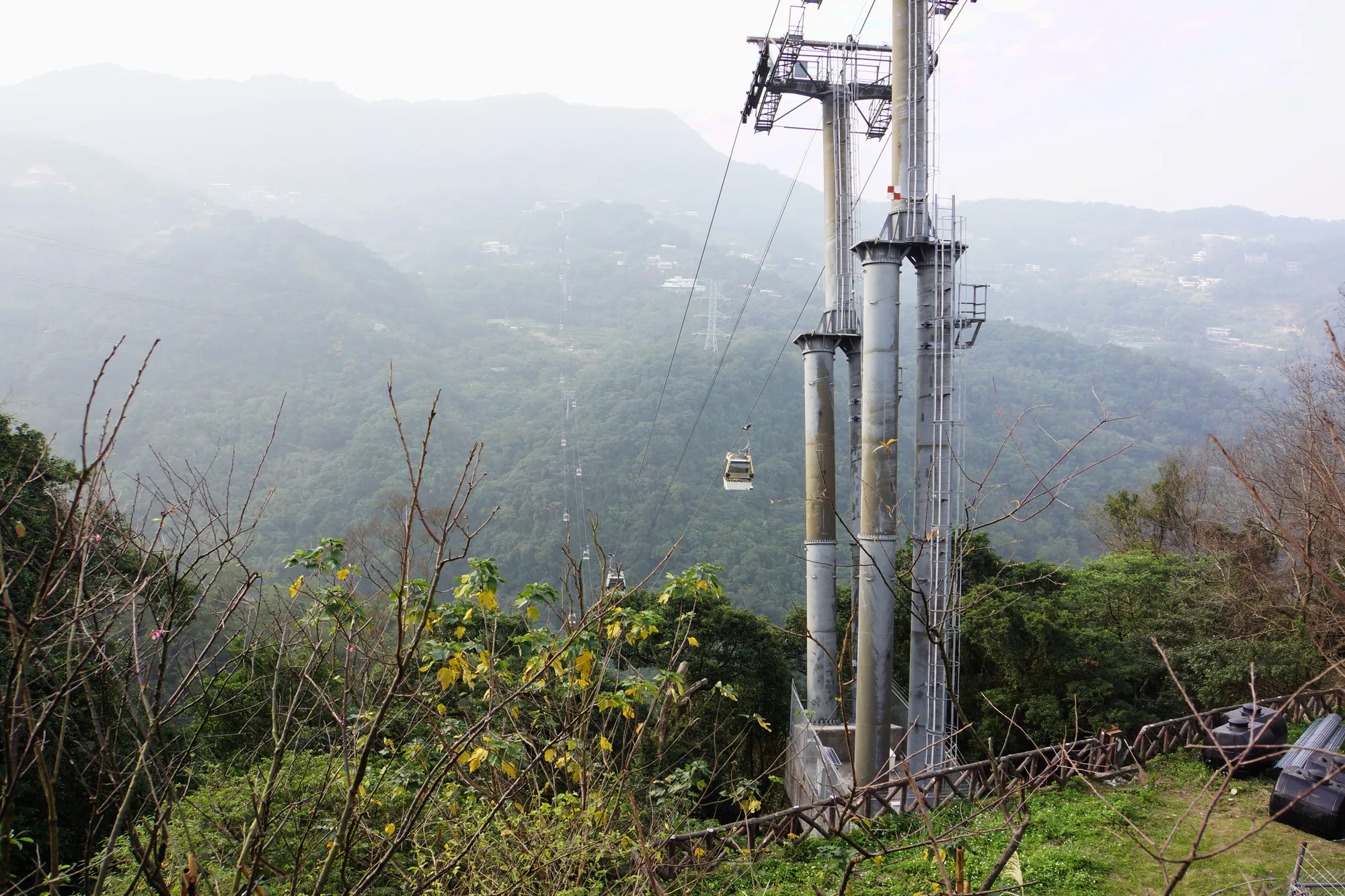 Maokong Gondola cable-car cabins on grey towers descending over forested green tea hills in Taipei