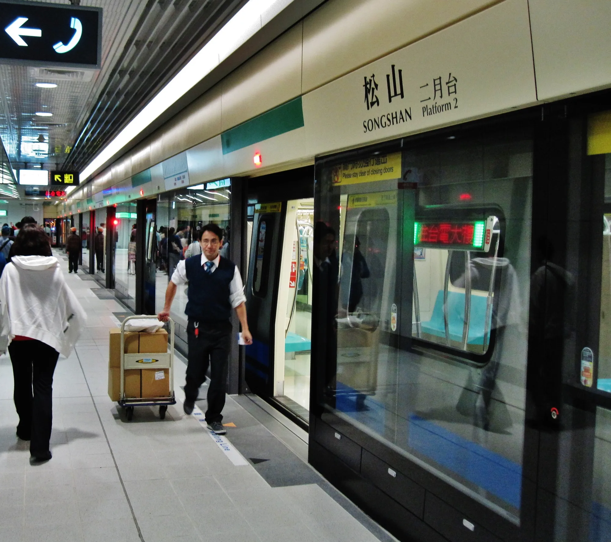 A Taipei Metro train at the platform of Songshan Station, with green-line platform signage