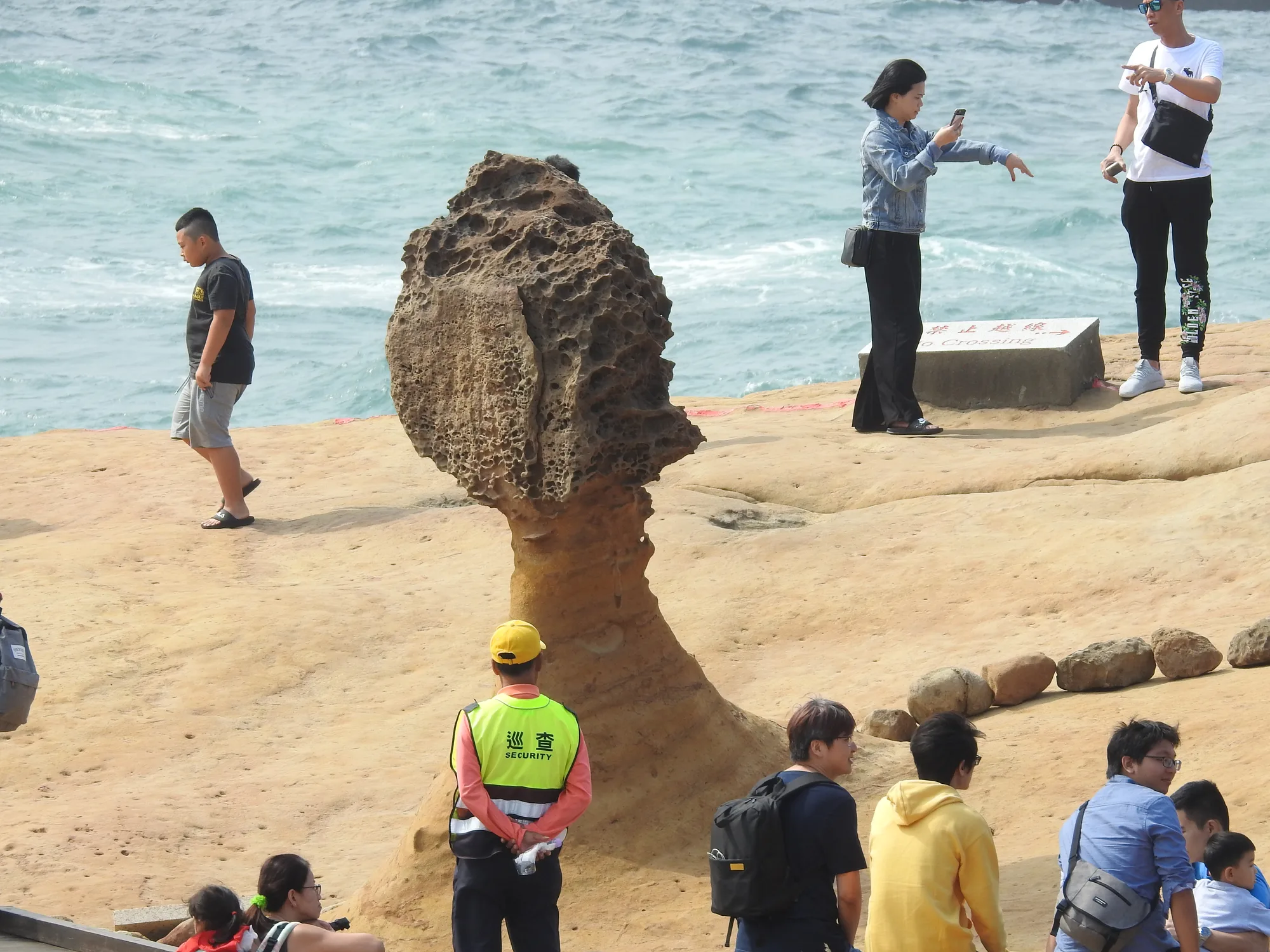 The Queen's Head mushroom-rock formation at Yehliu Geopark on Taiwan's north coast, with tourists beside it